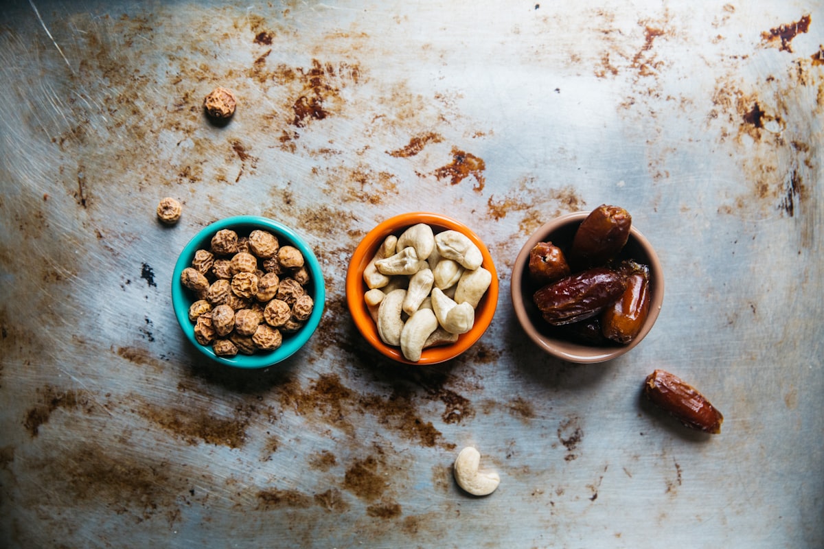 Three colorful bowls containing walnuts, cashews, and dates - healthy intermittent fasting snacks